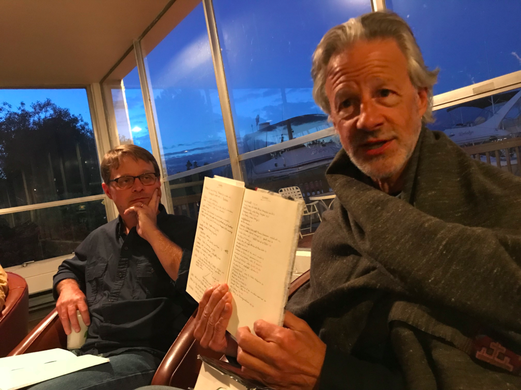Keynote poet Andrew Schelling shows off his notebook while Jared Leising looks on